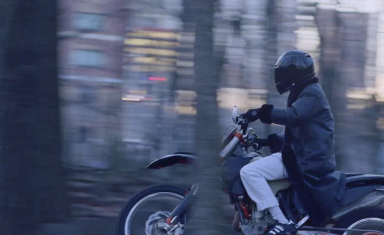 Person rides motorcycle on road through woods