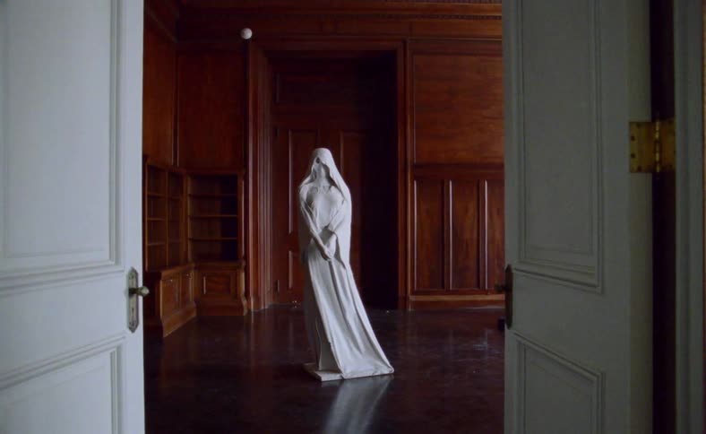 Marble statue of a woman in robes inside empty room in a mansion