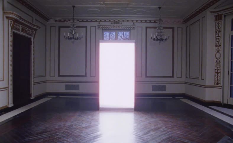 A room with chandeliers and a doorway with light