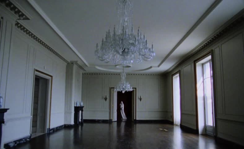A room with hardwood floors chandeliers and windows