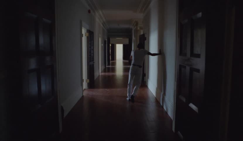 Man staggers down long ornate hall