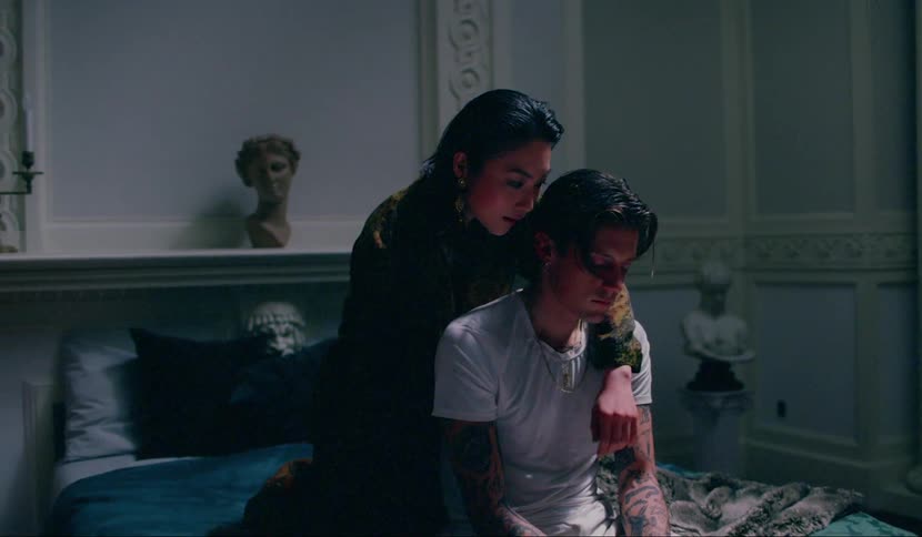 A woman covers a mans eyes in bed