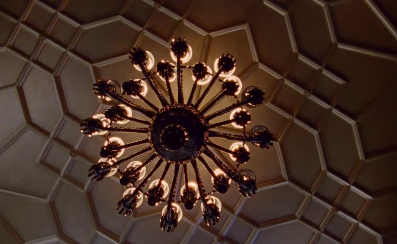 A chandelier hangs from an ornate ceiling