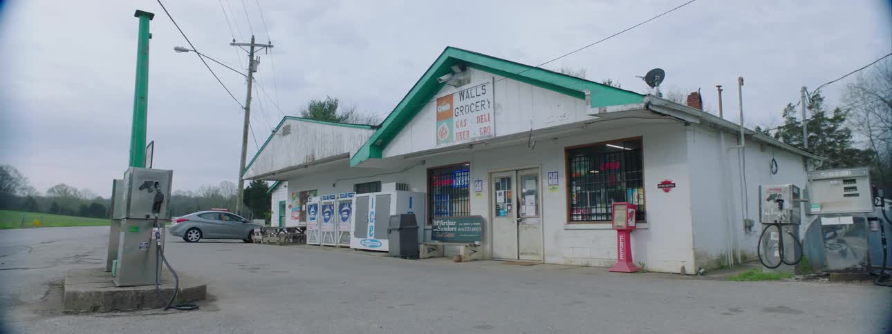 A gas station with a car and trees in the background