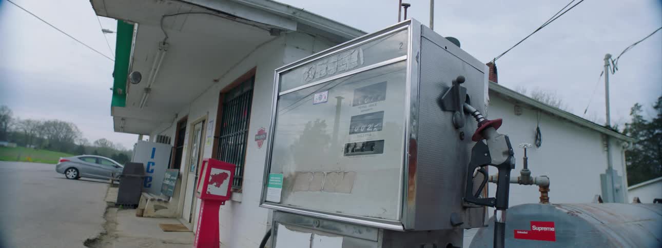 The gas station with a car and a field in the background