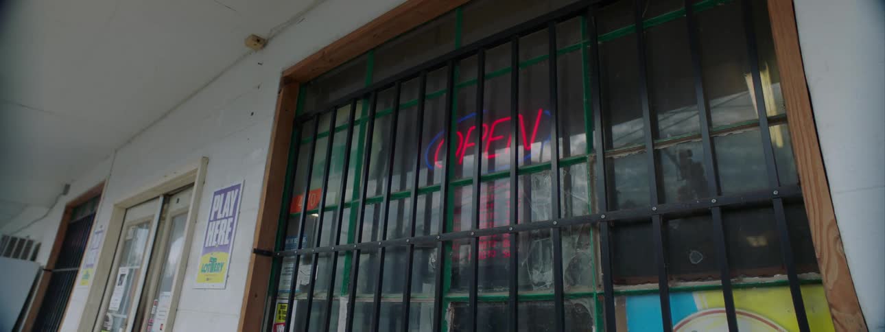 Open sign behind window store with security grill