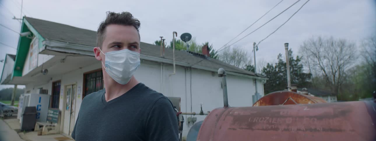 A man stands outside store with a mask on