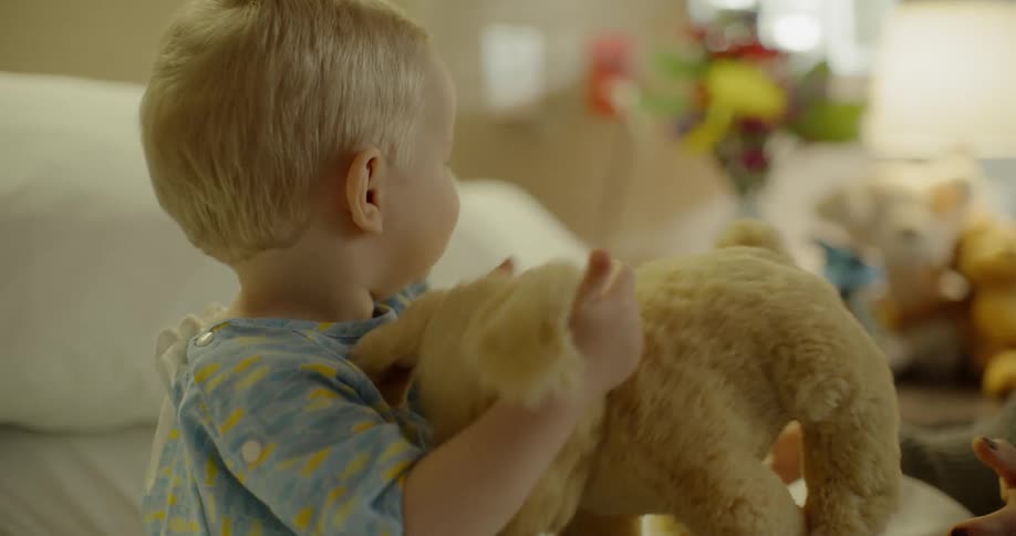 A mother plays with her son in a hospital room