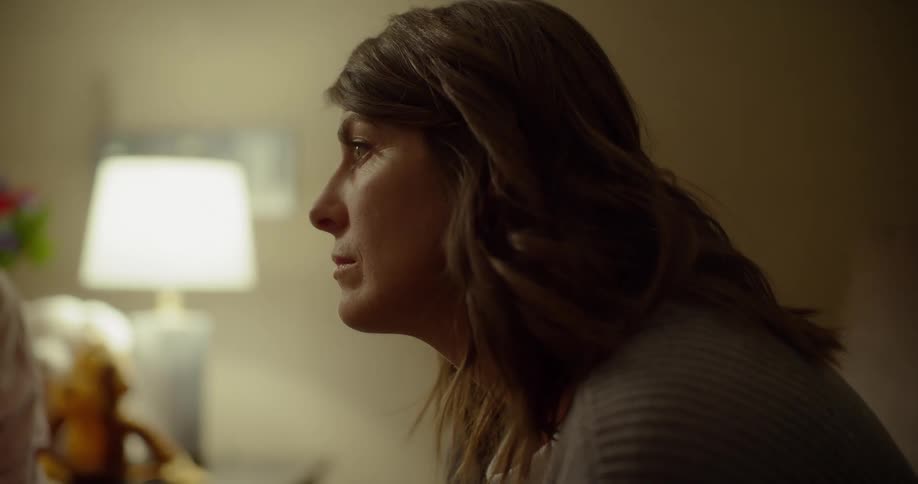 A woman sits leaning forward in the room