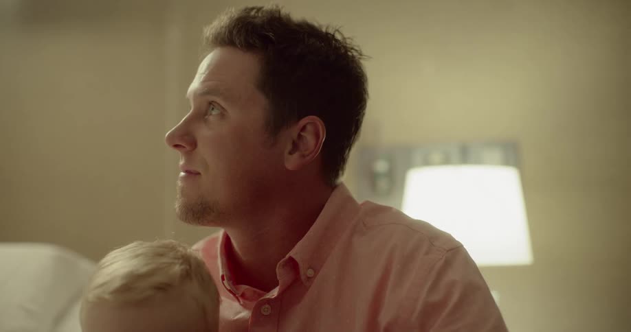 A father looks up with his son in his lap