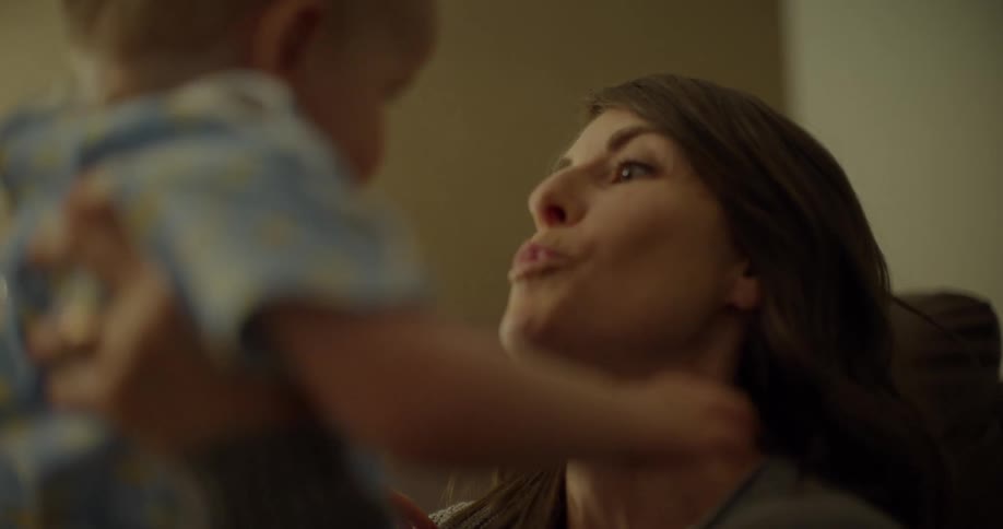 A woman sitting down on the couch holding and hugging a child