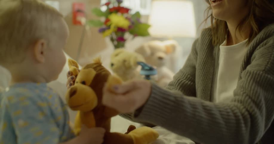 A mother plays with a stuffed monkey with a child