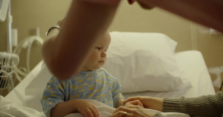 A child sits in a hospital bed with people around him