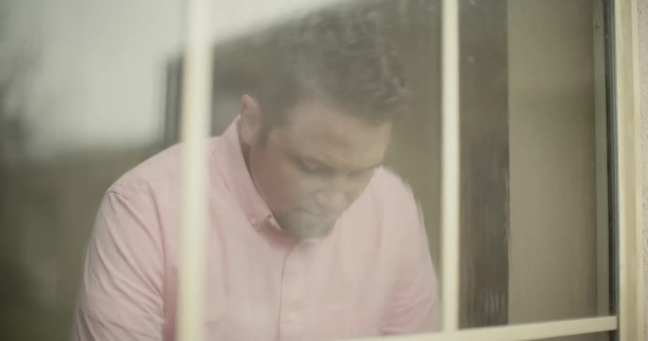A man looking solemnly out a window