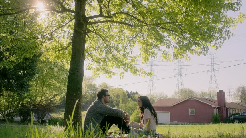 A man and woman sit under a tree talking