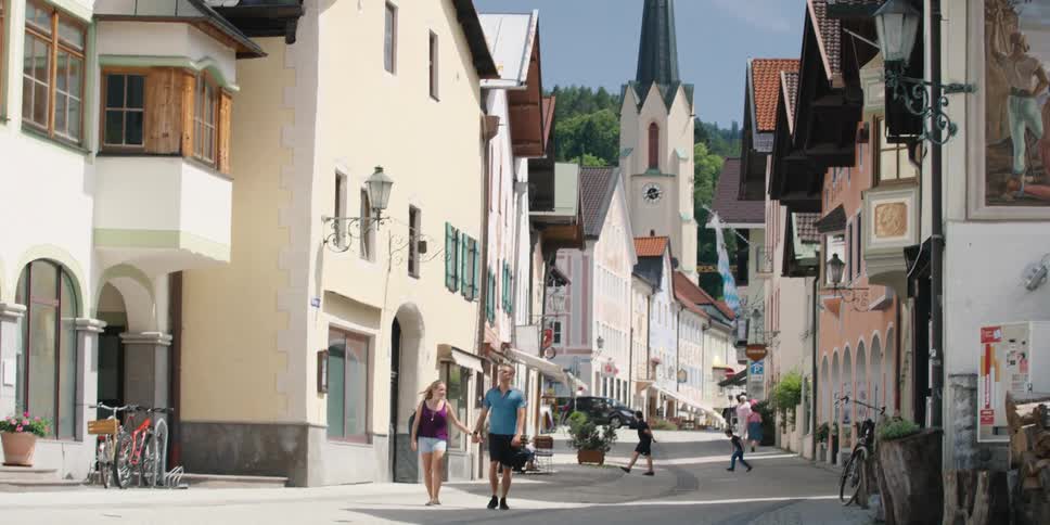 A couple holds hands as they walk down the street of a beautiful village on sunny day