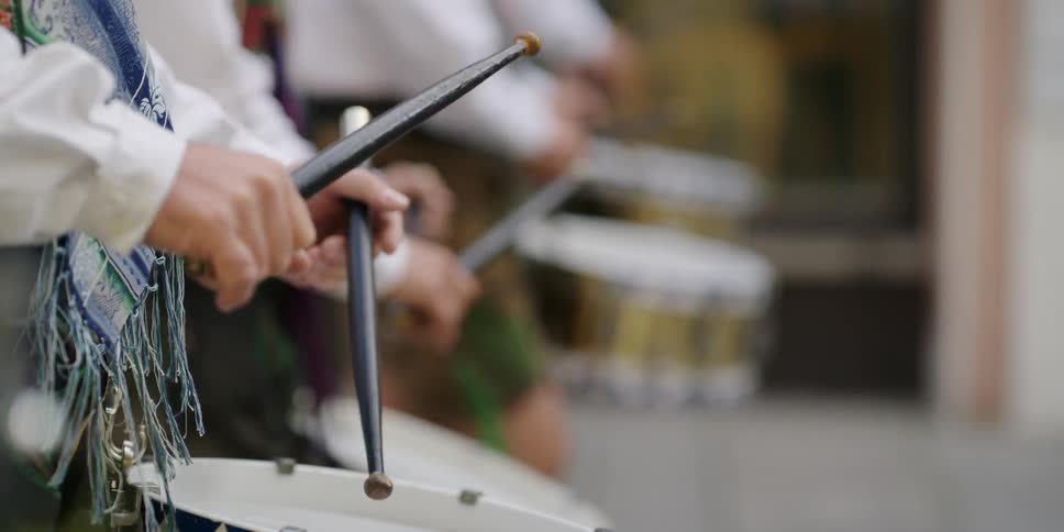 People are marching while playing a drum
