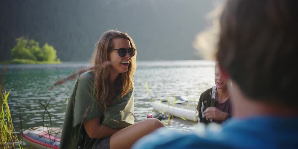 People sit together by the lake talking