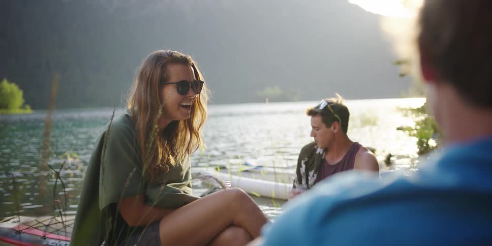 People sit around drinking and laughing by the lake