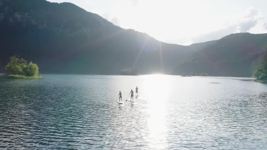 Three people paddle board in a lake
