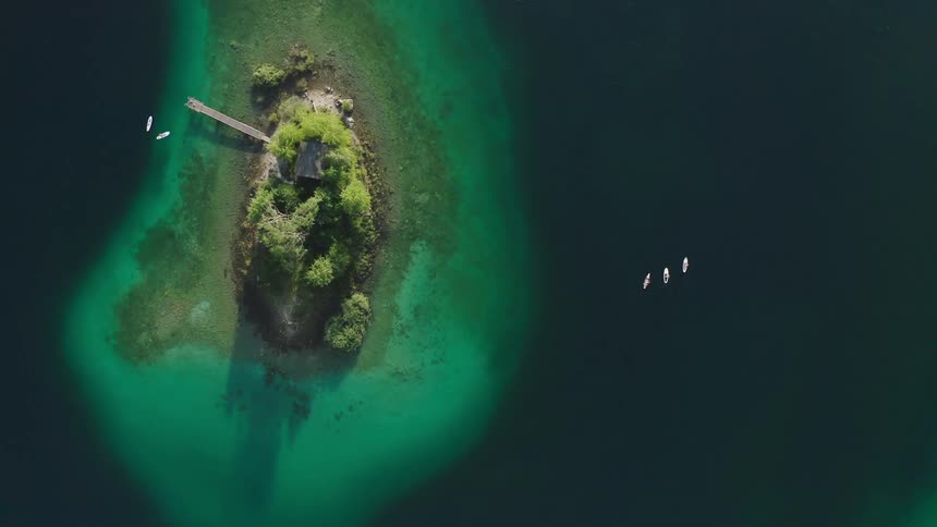 People rowing kayaks around island in lake at day