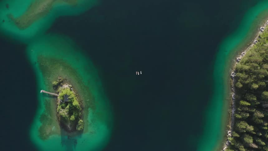Three people are on surfboards in the lake below