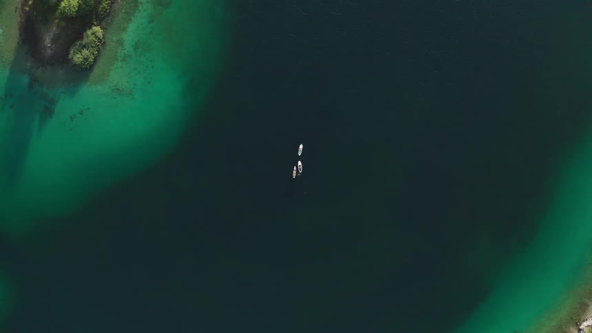 Birds eye view of three boats cruising in the ocean near an island