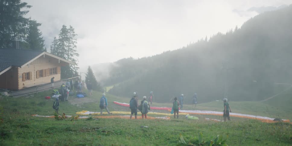 Group of people practicing paragliding in forest covered mountains