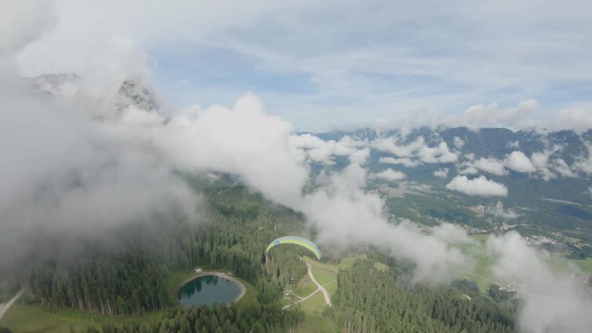 A skydiver goes through clouds near a mountain range