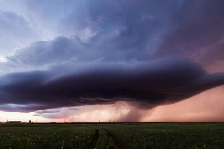 Storm front spins as it flows across green plains