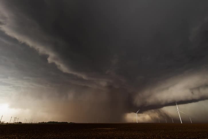 A rain-wrapped tornado slowly emerges from the dust and rain