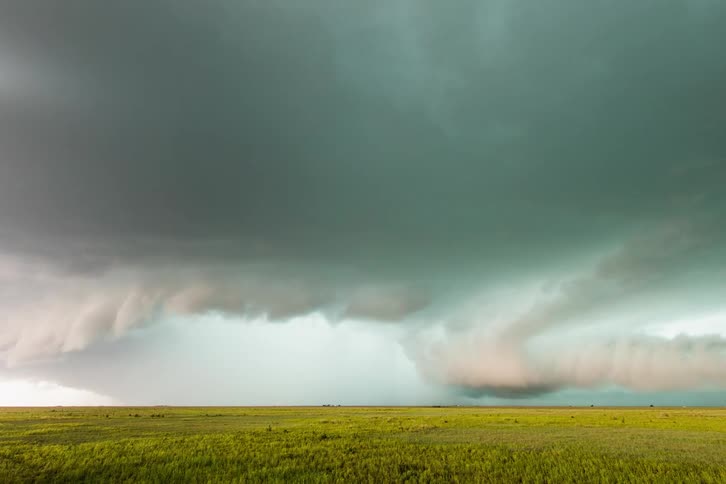 The storm rages in the distance on the green field