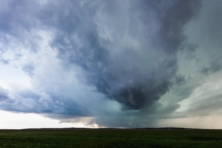A grassy plain with lightning and storm clouds above