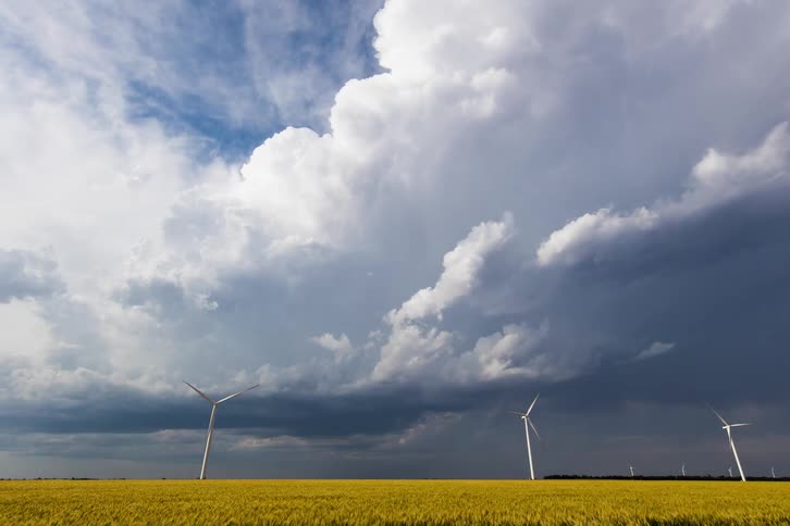 A building supercell behind some wind turbines