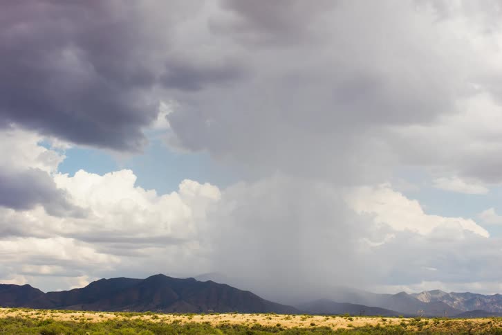 The storm rains water over the mountains