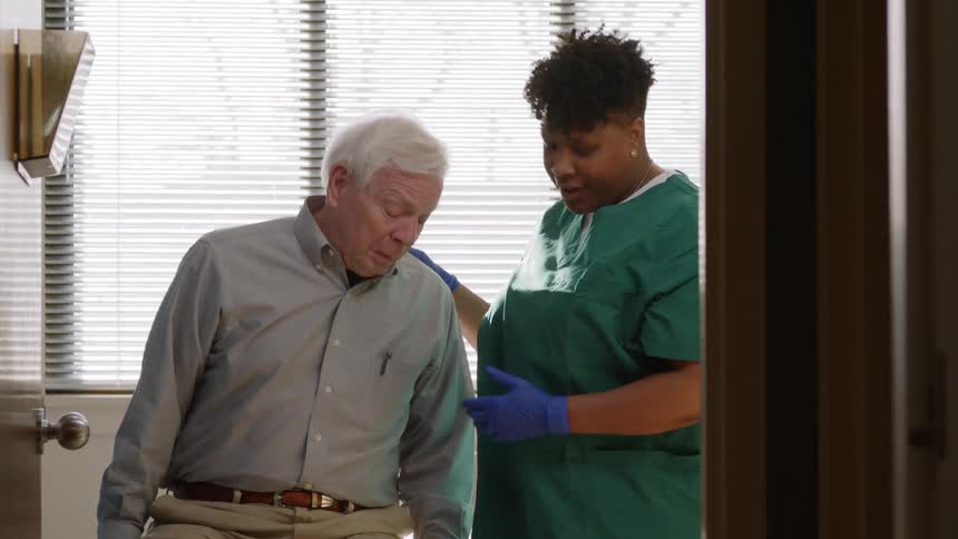 A nurse assisting an elderly man in a clinic