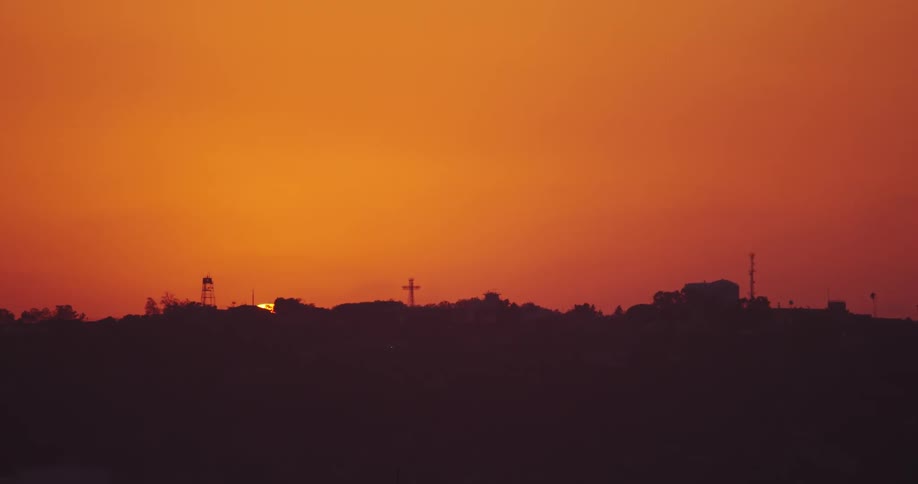 The sun slowly sets behind the hills