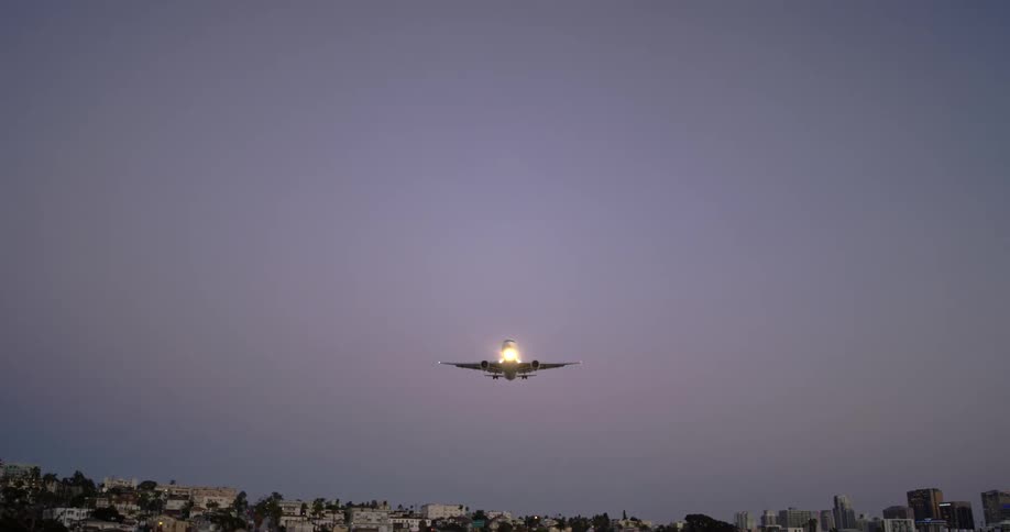 A plane glides over the city at sunset