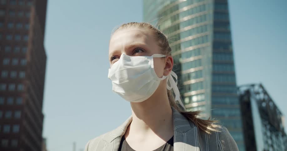 Woman wearing face mask stands on city street at day