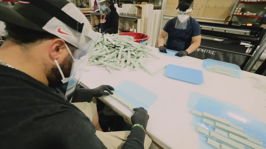 Workers manufacture items at long table