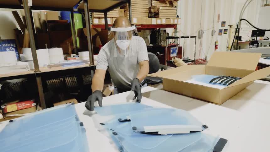 A man in a factory puts plastic clipboards in a box