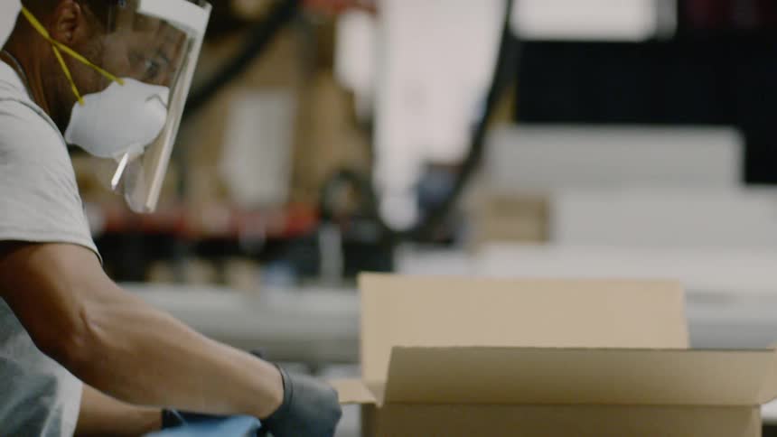 A man in a factory picks up plastic pieces