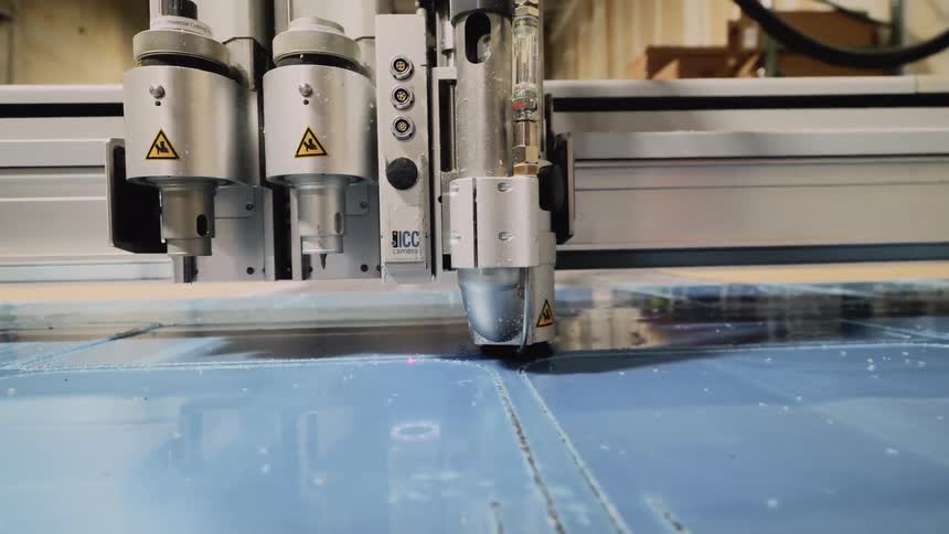 An automatic cutting machine follows a guide or program to cut out glass or plastic