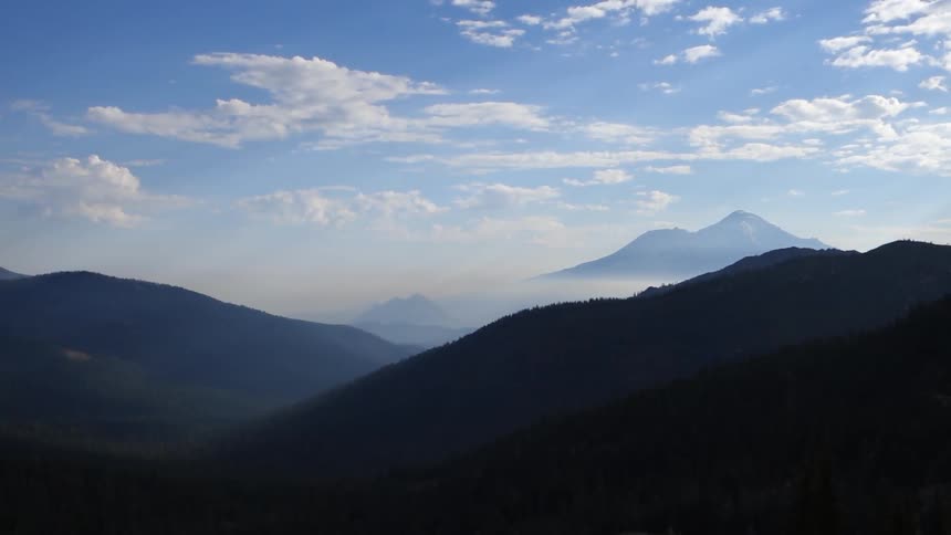Mountains peeking through fog and clouds on a sunny day