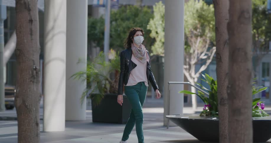 A woman in a face mask walking out of building in a city