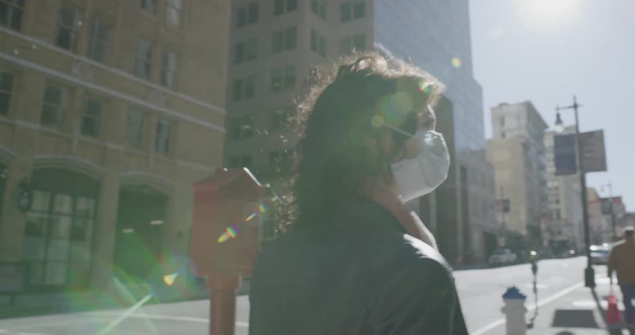 A woman wearing a mask is walking in a downtown area