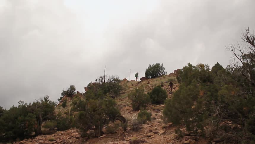 A hiker climbs up a hill on an overcast day