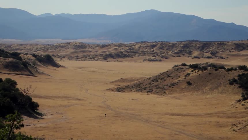 A person walking through a desert as seen from far away