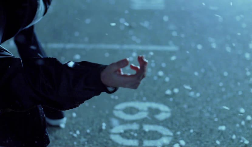 A man reaches his hand forward as snow falls