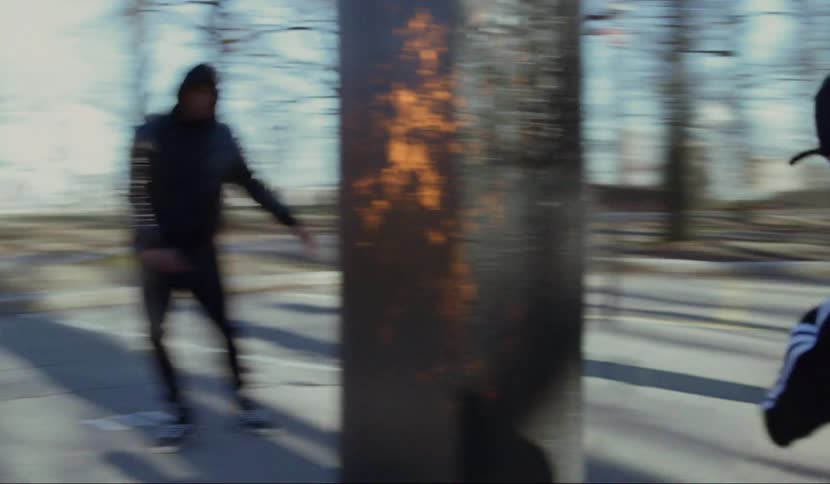 Group of men dance in parking lot among trees near building